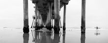  Surfer at the Huntington Beach California Pier at low tide, black and white, panoramic