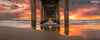 A panoramic photograph of underneath the Manhattan Beach pier with an orange sunset