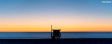  A panoramic photo of a lifeguard tower in Hermosa Beach / Manhattan Beach (Los Angeles California) at sunset with golden ad blue skies over the Pacific Ocean.