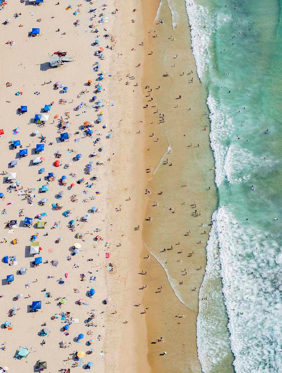 Color aerial photo of Manhattan Beach in Los Angeles with beach umbrellas, a lifeguard tower and the ocean