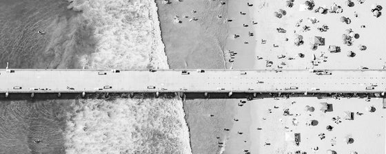 Black and white panoramic aerial photo of Manhattan Beach Pier in Los Angeles with beach umbrellas, sand and the ocean