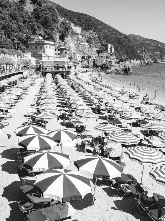 Monterosso Beach with striped umbrellas in black and white in Italy looking East.