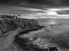 The palos verdes vicente lighthouse during sunset with pink clouds and calm water in black and white.
