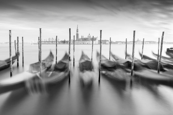 Black and white photo of gondolas on the Grand Canal in Venice Italy, with the Church of San Giorgio Maggiore in the distance