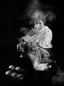  Black and white photo of a woman making coffee in Ethiopia, shrouded in smoke