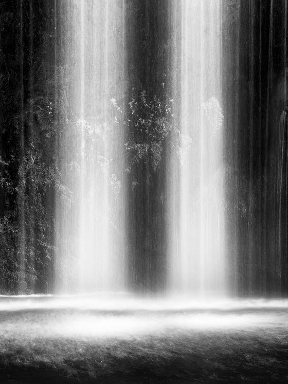 An abstract, vertical, black and white photo of a waterfall