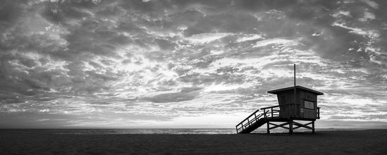 A panoramic photo of a lifeguard tower in Hermosa Beach / Manhattan Beach (Los Angeles California) at sunset, in black and white