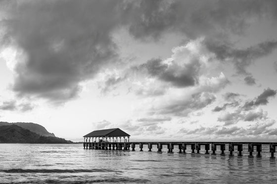 A photograph of Hanalei pier on Kauai during sunset, in black and white
