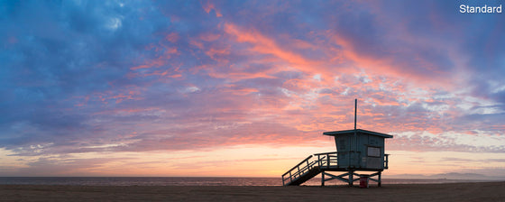A panoramic photo of a lifeguard tower in Hermosa Beach / Manhattan Beach (Los Angeles California) at sunset with pink clouds and a blue sky