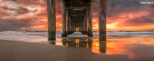 A panoramic photograph of underneath the Manhattan Beach pier with an orange sunset