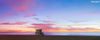 A panoramic photo of a lifeguard tower in Manhattan Beach (Los Angeles California) at sunset, with Cataline Island in the distance.