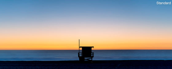 A panoramic photo of a lifeguard tower in Hermosa Beach / Manhattan Beach (Los Angeles California) at sunset with golden ad blue skies over the Pacific Ocean.