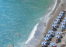  Blue ocean water with 17 blue and white umbrellas on the right side of the horizontal photo.