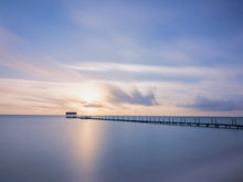  A photograph of a dock in the ocean during sunrise with a calm sky and calmer sea on Cuba's northern coast