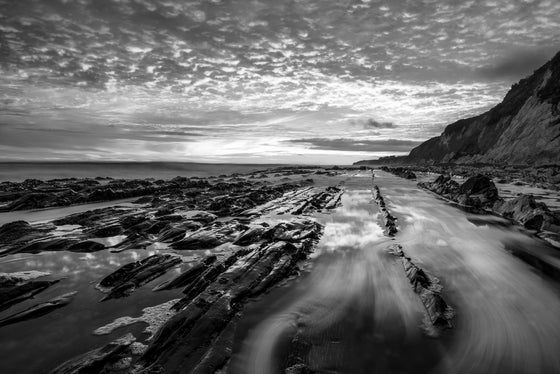 sunset and water in the rocks off of the central coast in California at sunset, in black and white