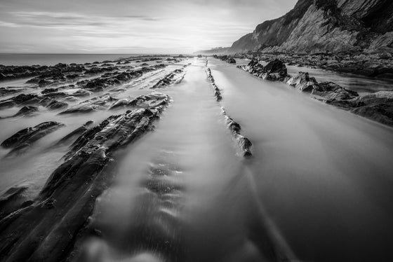 This photograph is taken during sunset along the central coast of California. The water appears smooth because the photo uses a long exposure, black and white