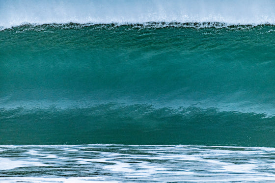 Big green wave before it crashes, looking like a solid wall of water