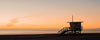 Hermosa Beach 8th street lifeguard tower at sunset with an orange sky and glassy blue water