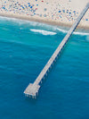 Color aerial photo of Hermosa Beach Pier in Los Angeles with beach umbrellas and a lifeguard tower