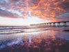 Hermosa Beach pier at sunset with clouds reflecting in the sand and a red sky