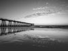 Hermosa Beach pier at sunset with clouds reflecting in the sand, in black and white