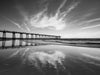 Hermosa Beach California pier, at sunset, with clouds reflected on the sand in the beach, in black and white