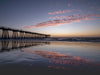 Hermosa Beach pier at sunset with clouds reflecting in the sand