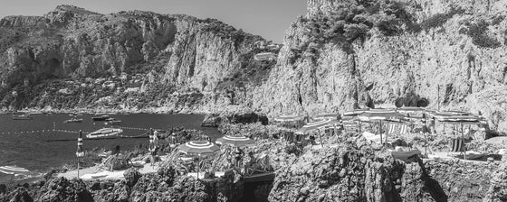 panoramic photo of La Fontelina beach club in Capri Italy with sunbathers in black and white