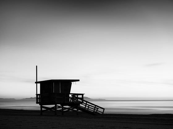 A lifeguard tower in Hermosa or Manhattan Beach California, with Catalina Island in the background, and smooth water, in black and white