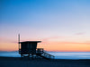 A lifeguard tower in Hermosa or Manhattan Beach California, with Catalina Island in the background, and smooth blue water and an orange and blue sky