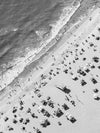 Black and white aerial photo of a beach in Los Angeles with beach umbrellas, a lifeguard tower and the ocean