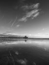 The Manhattan Beach Pier California at low tide, with the clouds reflected in the sand, in black and white