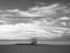A Manhattan Beach lifeguard tower, in Los Angeles, at sunrise, with soft clouds over the Pacific Ocean, in black and white