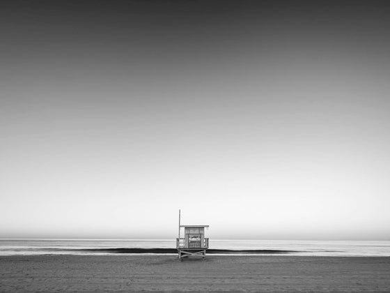 A minimalistic photo of a lifeguard tower in Hermosa Beach / Manhattan Beach (Los Angeles California) at sunrise., in black and white