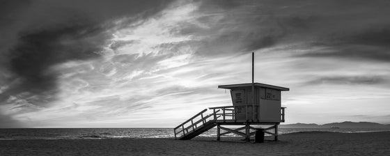 A panoramic photo of a lifeguard tower in Hermosa Beach / Manhattan Beach (Los Angeles California) at sunset., in black and white