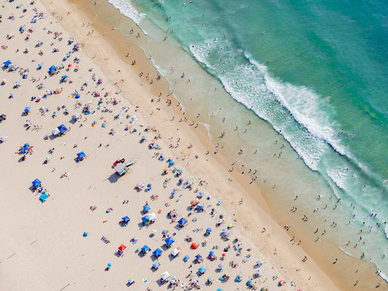 Color aerial photo of Manhattan Beach in Los Angeles with beach umbrellas, a lifeguard tower and the ocean