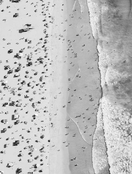 Black and white aerial photo of Manhattan Beach in Los Angeles with beach umbrellas, a lifeguard tower and the ocean