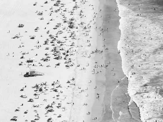 Black and white aerial photo of Manhattan Beach in Los Angeles with beach umbrellas, a lifeguard tower and the ocean