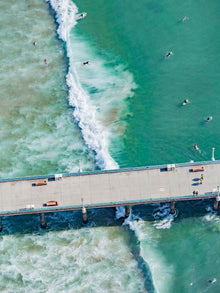  Color aerial photo of Manhattan Beach Pier in Los Angeles with surfers, swimmers, and a wave breaking in the Pacific Ocean
