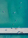 Color aerial photo of Manhattan Beach Pier in Los Angeles with surfers and swimmers in the Pacific Ocean