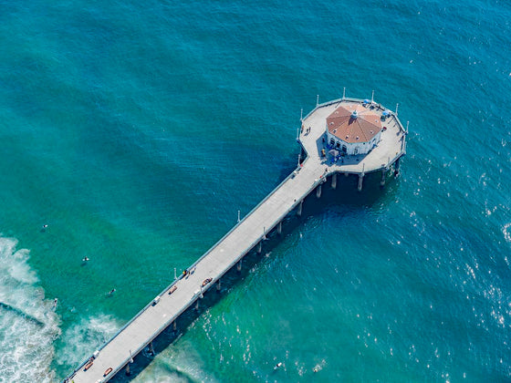 Color aerial photo of Manhattan Beach Pier in Los Angeles with beach umbrellas, sand and the ocean
