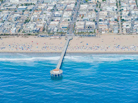 Color aerial photo of Manhattan Beach Pier in Los Angeles with beach umbrellas, sand and the ocean