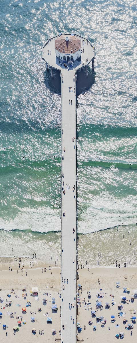 Color vertical panoramic aerial photo of Manhattan Beach Pier in Los Angeles with beach umbrellas, sand and the ocean