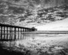Manhattan beach pier at sunset with reflections of the clouds in the sand in black and white