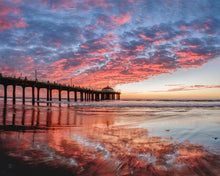  Manhattan beach pier at sunset with a red fiery sky and reflections of the clouds in the sand