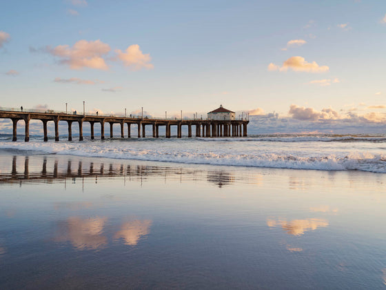 Manhattan Beach California pier, at sunset, with clouds reflected on the sand in the beach