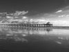 The Manhattan Beach Pier in California, at super low tide, with a reflection of the sky in the sand, in black and white