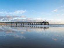  The Manhattan Beach Pier in California, at super low tide, with blue sky and a blue reflection of the sky in the sand