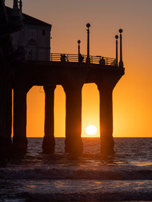   Manhattan Beach  Pier  orange sunset shining through the pier's pilings about to reach the horizon. 
