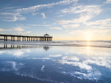  manhattan beach pier at sunset with a low tide and clouds reflecting in the sand